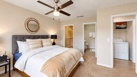 Furnished bedroom with a ceiling fan, walk-in closet opening, and nearby bathroom at Icon Cartersville Apartments.