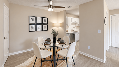 Dining area with a round glass table, four chairs, and a view into the kitchen at Icon Cartersville Apartments.