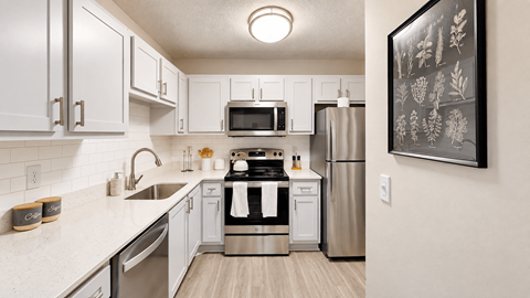 Apartment kitchen with white cabinets, subway tile backsplash, and stainless steel appliances at Icon Cartersville.