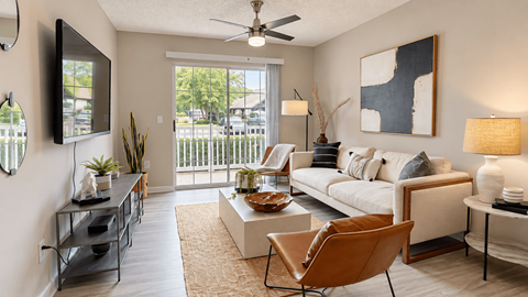 Furnished living room with a sofa, accent chairs, ceiling fan, and sliding door to a balcony at Icon Cartersville Apartments.