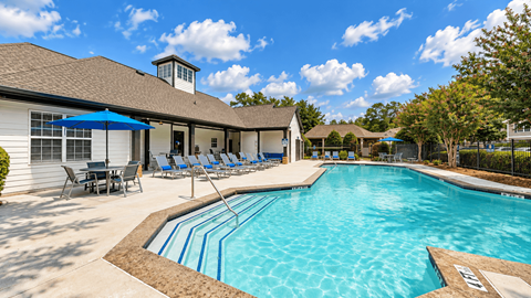 View across the Icon Cartersville swimming pool toward lounge chairs, umbrellas, and the clubhouse.