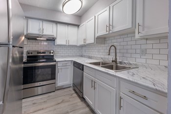 Updated Kitchen upgraded kitchen with white subway tile backsplash, white cabinets and brushed nickel hardware with gooseneck faucet. Euro washer and dryer, and stainless steel stove and refrigerator. vinyl plank flooring. - Photo Gallery 5