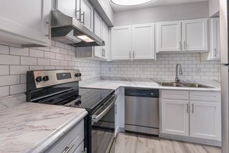 upgraded kitchen with white subway tile backsplash, white cabinets and brushed nickel hardware with gooseneck faucet.  Euro washer and dryer, and stainless steel stove and refrigerator