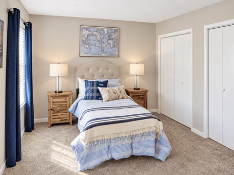 Bedroom with carpet, closet storage, and blue-accented furnishings at Madison Park Apartments & Townhomes in Birmingham, AL.