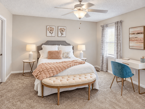 Spacious apartment bedroom with carpet, ceiling fan, window, and workspace at Madison Park Apartments & Townhomes in Birmingham, AL.