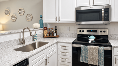 Apartment kitchen with white cabinets, stainless steel appliances and subway tile backsplash at Seaside Grove Apartments in Myrtle Beach, SC.