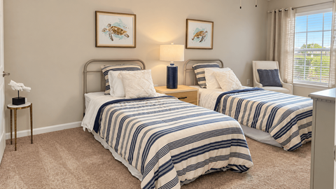 Furnished bedroom with two twin beds, striped bedding and sea turtle artwork at Seaside Grove Apartments in Myrtle Beach, SC.
