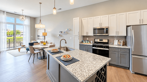 Apartment kitchen with an island, two-tone cabinets, stainless steel appliances and an adjacent dining area at VER at Proscenium in Carmel, IN.