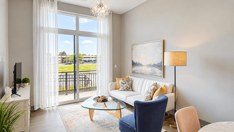 Furnished living room with a sofa, blue accent chair and glass doors to a balcony at VER at Proscenium in Carmel, IN.