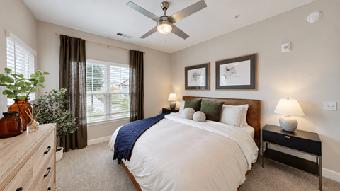 Furnished apartment bedroom with wood bed frame, ceiling fan and large windows at The View on Canton in Cartersville, GA.
