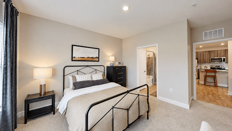 Furnished apartment bedroom with metal bed frame, dresser and adjoining bathroom at The View on Canton in Cartersville, GA.