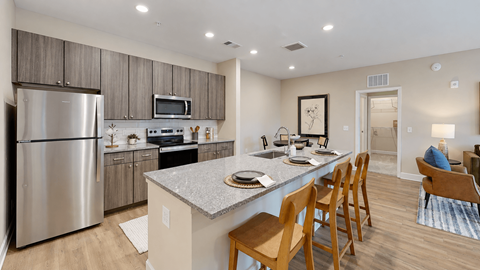 Apartment kitchen with stainless steel appliances, wood-grain cabinets and island seating at The View on Canton in Cartersville, GA.