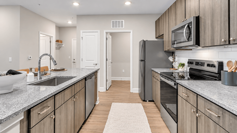 Apartment kitchen with stainless steel appliances, subway tile backsplash and island sink at The View on Canton in Cartersville, GA.