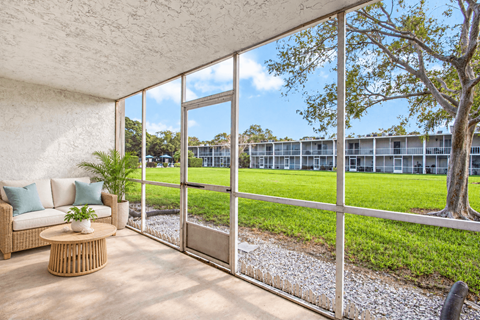 Exterior of Waterchase Apartments in Largo, FL, with trees beneath a blue sky.