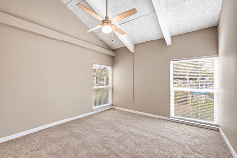 Unfurnished bedroom with exposed ceiling beams, a ceiling fan and carpet at Waterchase Apartments in Largo, FL.