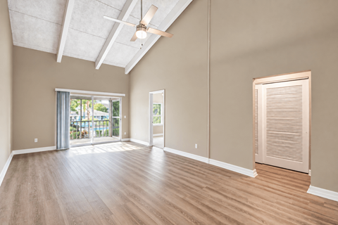 Unfurnished living room with a vaulted ceiling, exposed beams and balcony doors at Waterchase Apartments in Largo, FL.