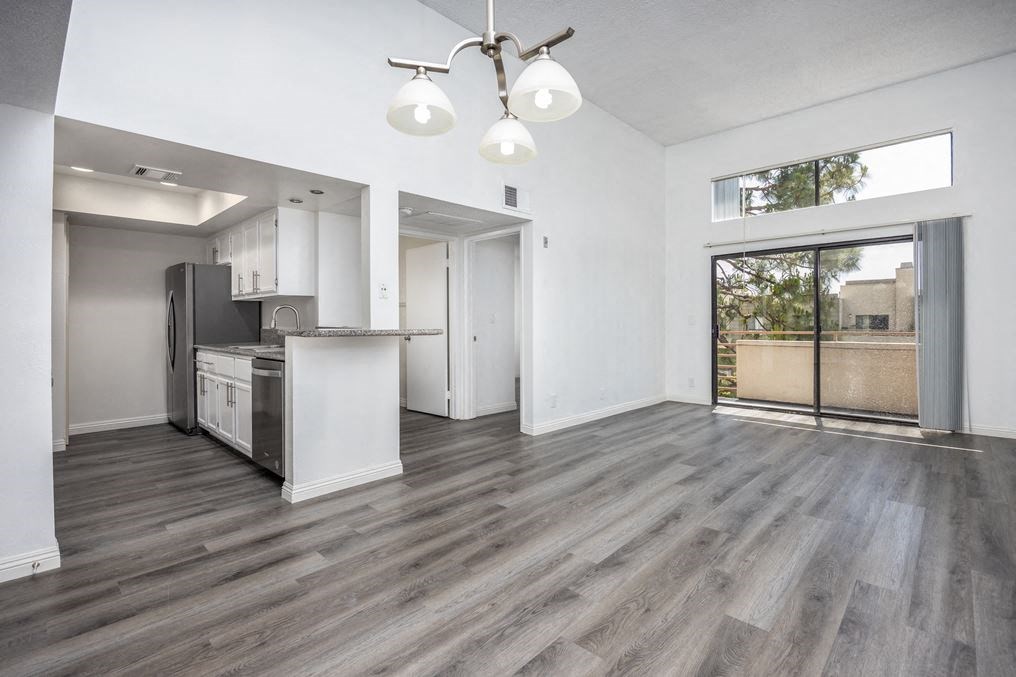 an empty living room with a kitchen and a sliding glass door