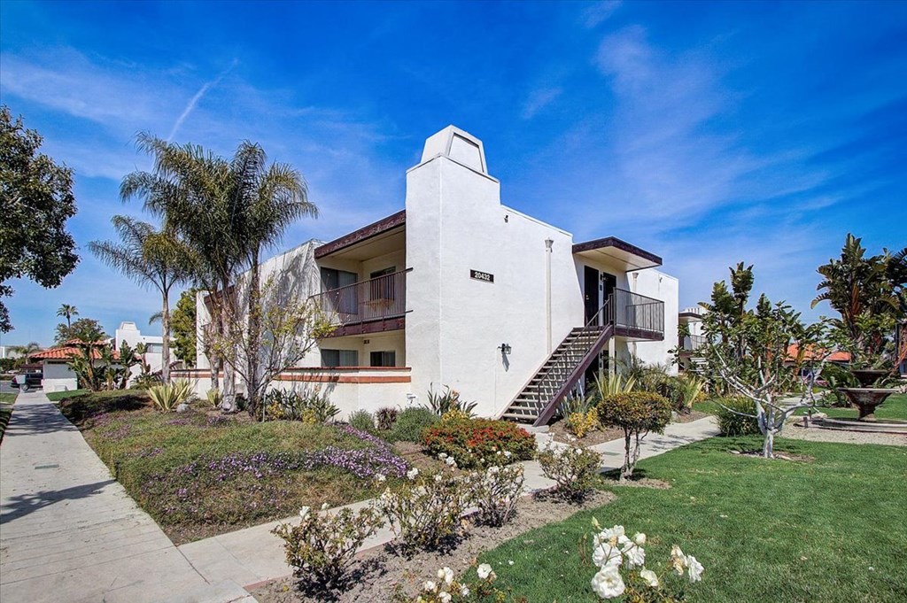 a white house with palm trees in the foreground and a blue sky in the background