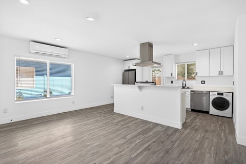 A kitchen with white cabinets and a wooden floor.