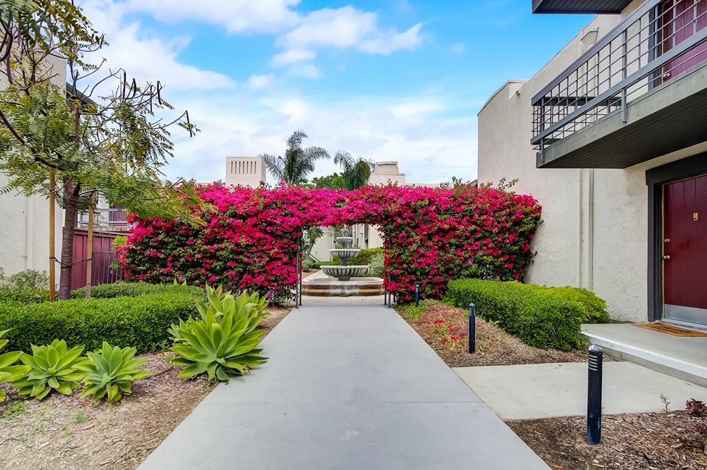 a walkway with a fountain in front of a building
