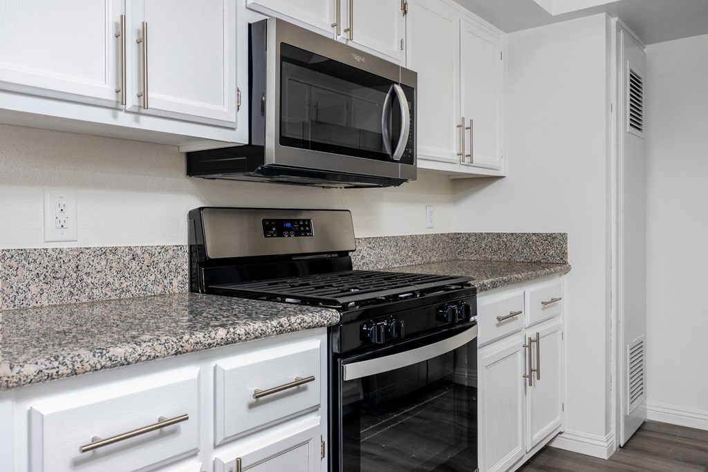 a kitchen with white cabinets and a black stove and microwave