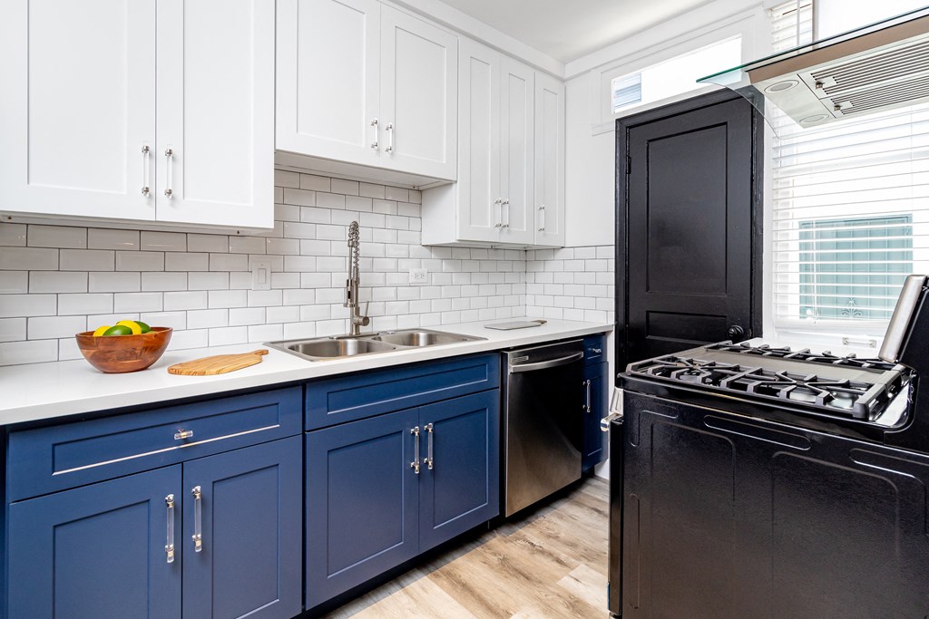 a blue and white kitchen with black appliances and white cabinets