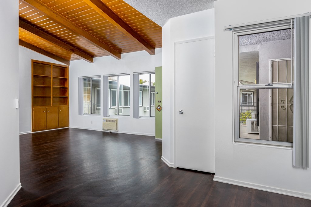 a living room with white walls and wood floors and a window and a door