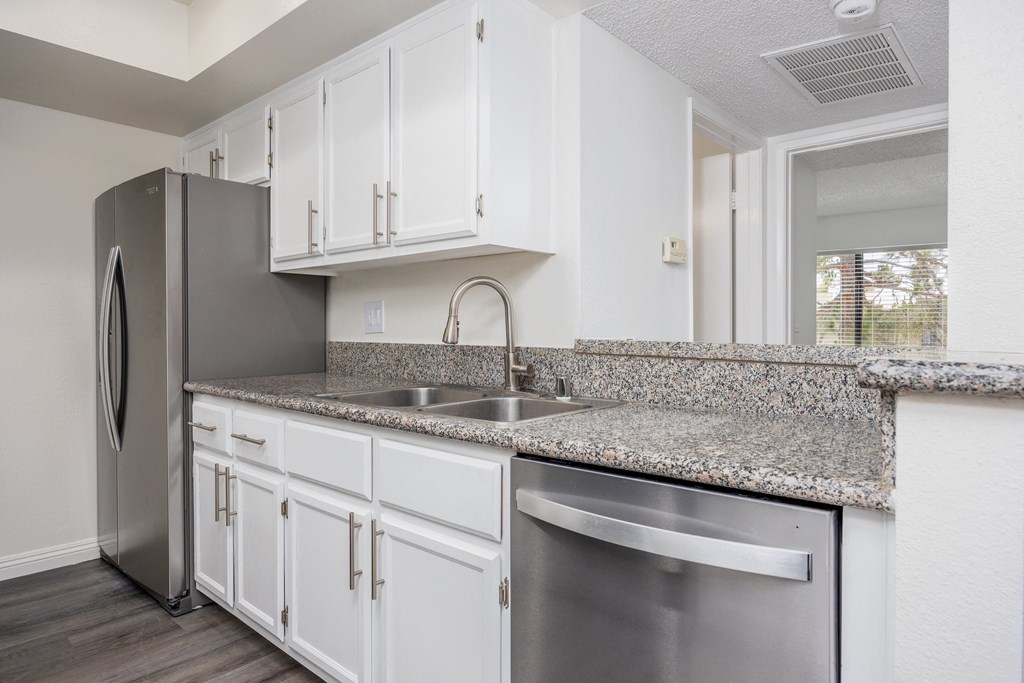 a kitchen with white cabinets and a stainless steel refrigerator