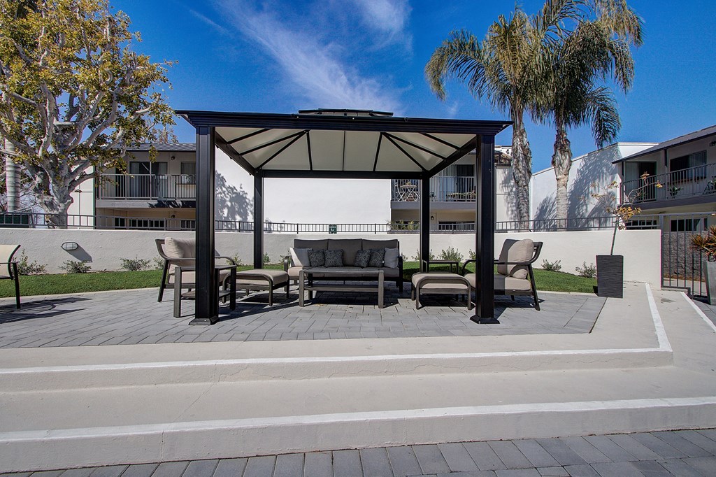 a patio with a couch and chairs under a gazebo