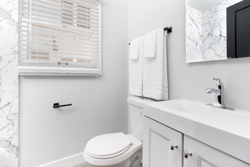 a white bathroom with a white toilet and a sink