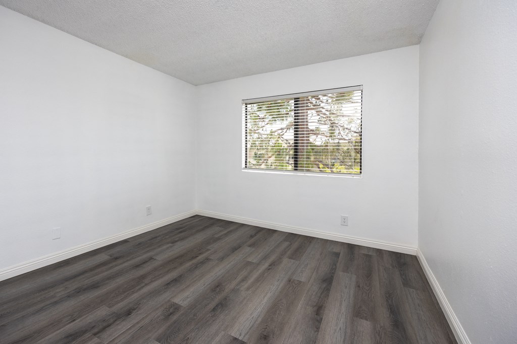 an empty room with wood floors and a window