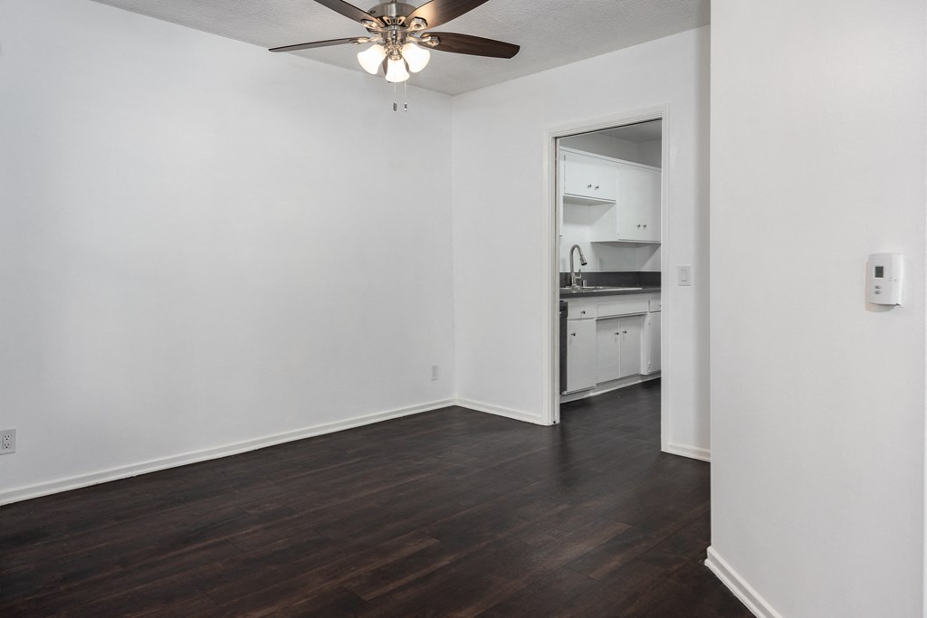 an empty living room with white walls and a ceiling fan
