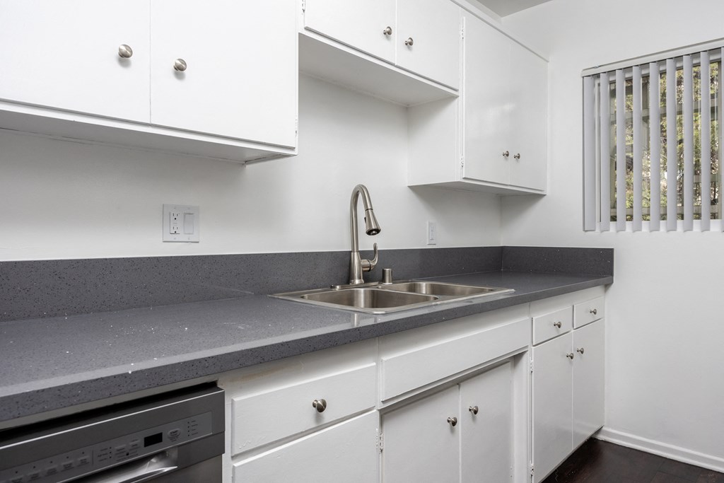 an empty kitchen with white cabinets and a sink