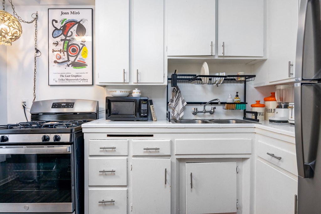 a kitchen with white cabinets and a stove and a sink