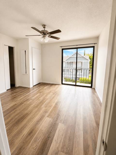 A room with a ceiling fan and sliding glass doors.