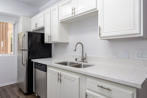 a kitchen with white cabinets and a sink and a refrigerator