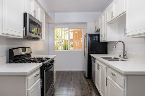 a kitchen with white cabinets and black appliances and a window