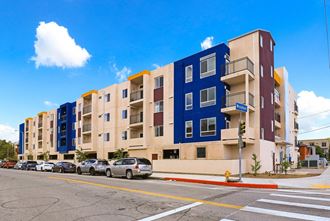a picture of an apartment building with cars parked in front of it