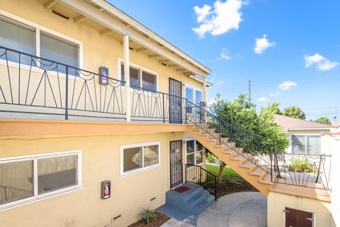 A yellow building with a black railing on the balcony.