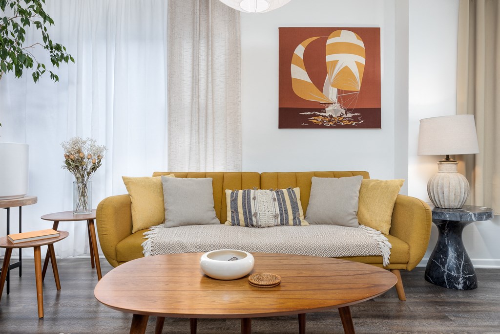 a living room with a yellow couch and a wooden table