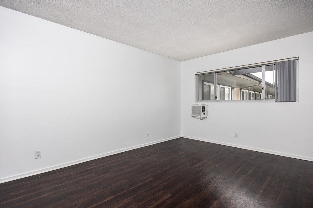 an empty room with white walls and wood floors and a window