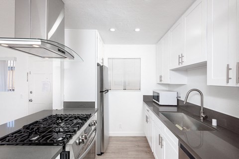 a kitchen with white cabinetry and black countertops