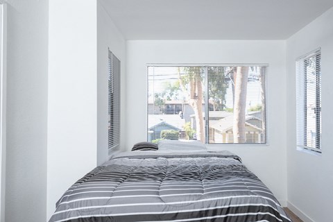 a small bedroom with a bed and a large window