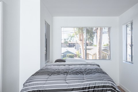 A bedroom with a bed and a window with blinds.