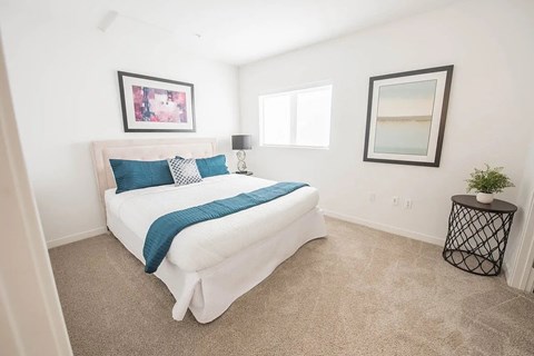 A bedroom with a white bed and a blue pillow.
