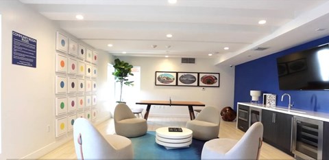 A modern living room with a blue rug and white chairs.