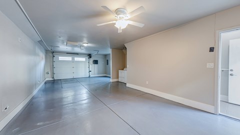 A spacious room with a ceiling fan and a door on the right side.