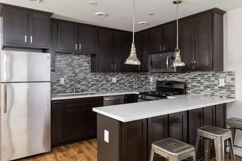 A kitchen with dark wood cabinets and a white counter.