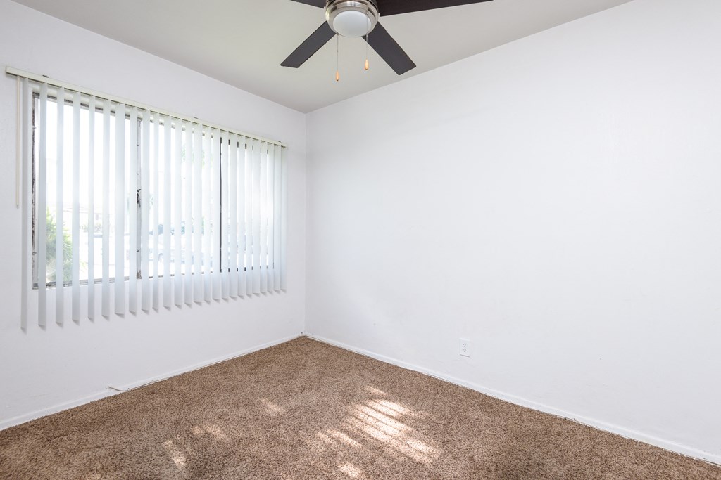 a bedroom with white walls and a ceiling fan