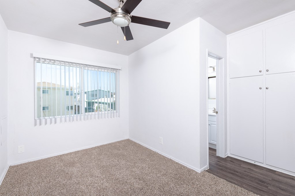 a bedroom with white walls and a ceiling fan